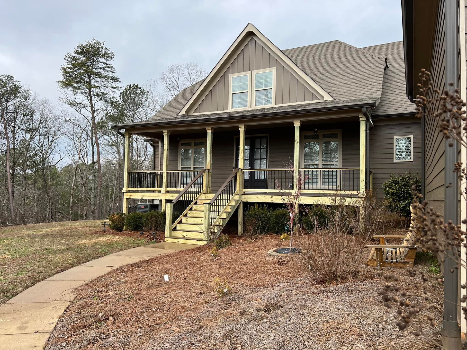 Brown house with porch, wooden stairs, and a walkway on a cloudy day.