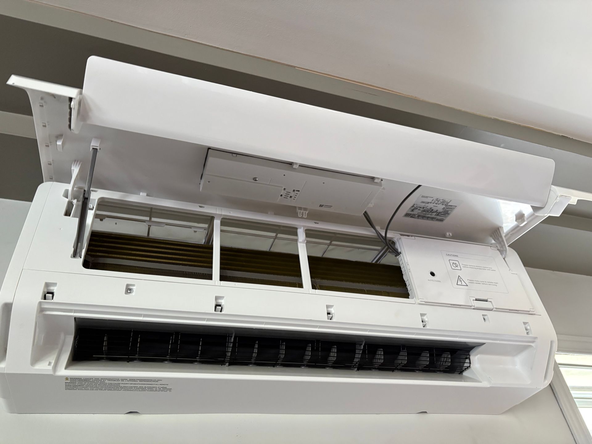 Un climatiseur mural blanc d'intérieur, dont le panneau avant est ouvert pour laisser apparaître les filtres internes.