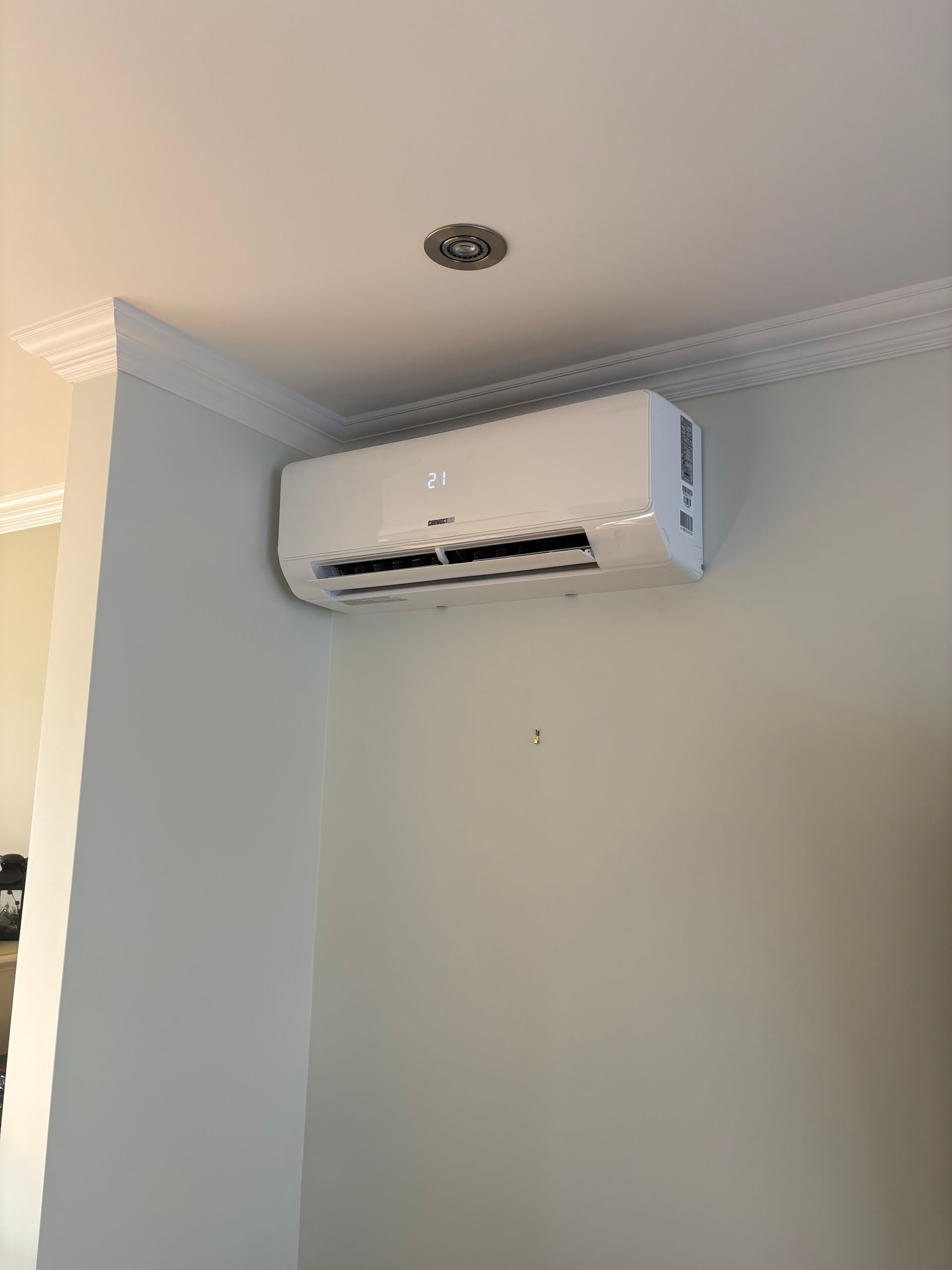 Un climatiseur mural blanc installé dans un coin de la pièce, près du plafond.