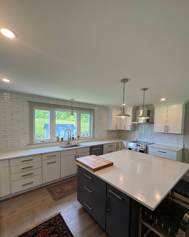 Modern kitchen with white and gray cabinets, island with countertop, and stainless steel appliances.