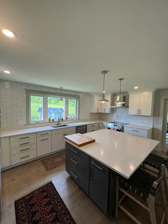 Modern kitchen with white cabinets, dark island, and light countertops.