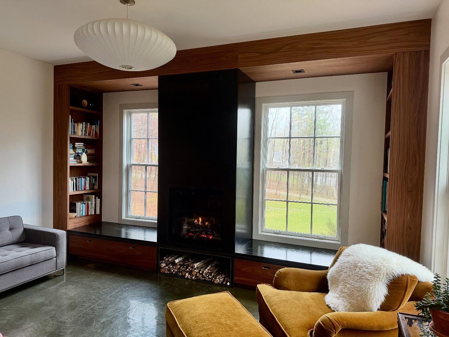Living room with black fireplace, windows, built-in bookshelves, and cozy seating.