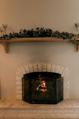 Fireplace with burning fire, brick surround, wooden mantel with greenery and sconces.