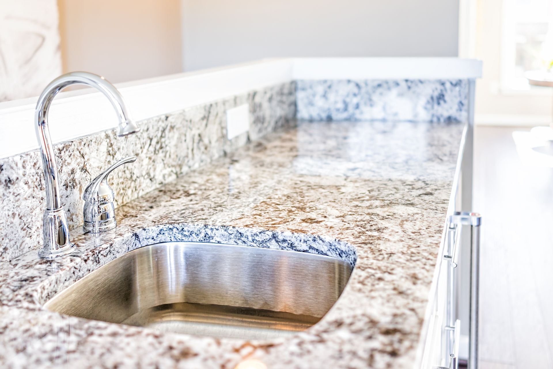 Stainless steel sink set in granite countertop with chrome faucet.