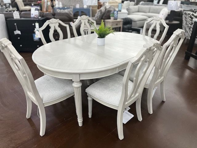 White oval dining table with six matching chairs.