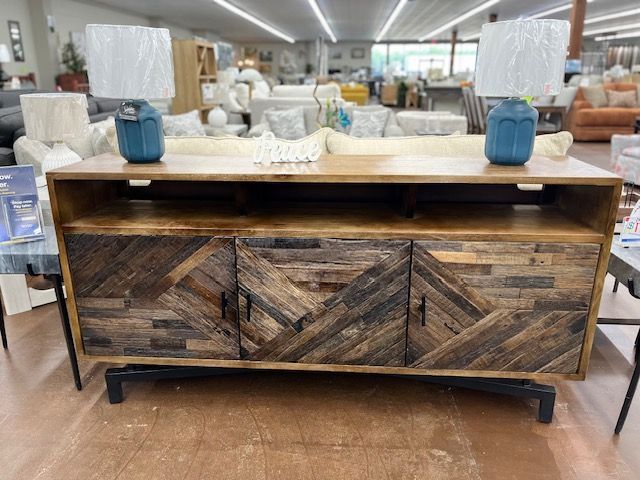 Wooden media console with geometric door design, two blue lamps on top.