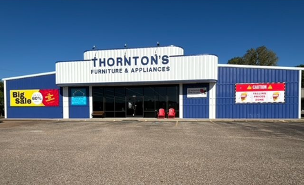 Thornton's Furniture & Appliances store front; blue building, cloudy sky, Big Sale sign, gravel parking.