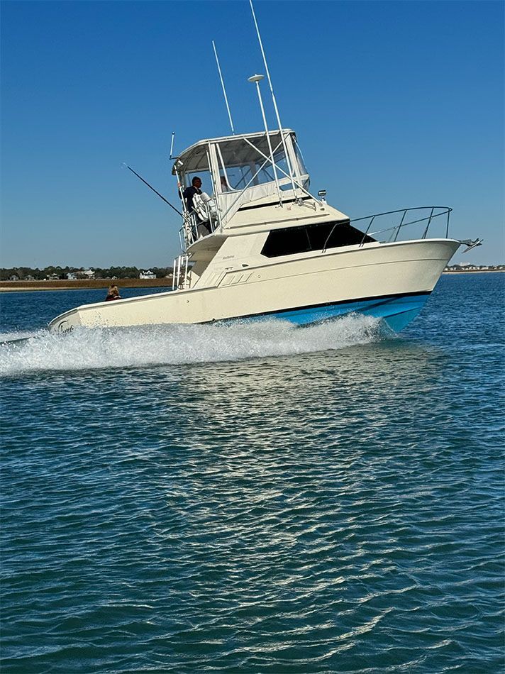 People fishing on a boat in the ocean under a cloudy sky.