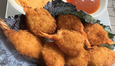 Golden fried shrimp on a plate with dipping sauces.