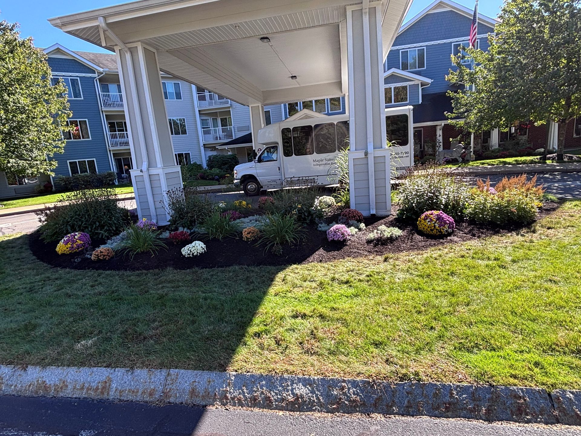A house with a landscaped yard including mulch, trees, and green grass.