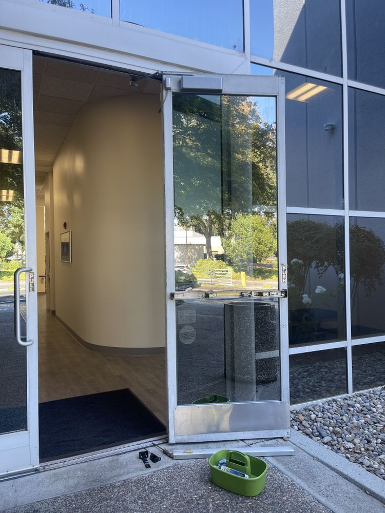 Open glass door with a toolbox, leading to a hallway with beige walls and a welcome mat.