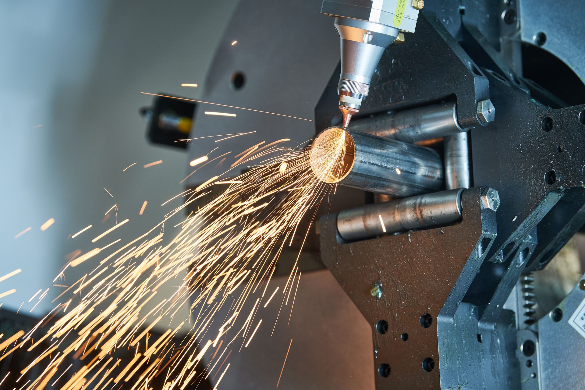 Une machine coupe un morceau de métal et des étincelles en sortent.