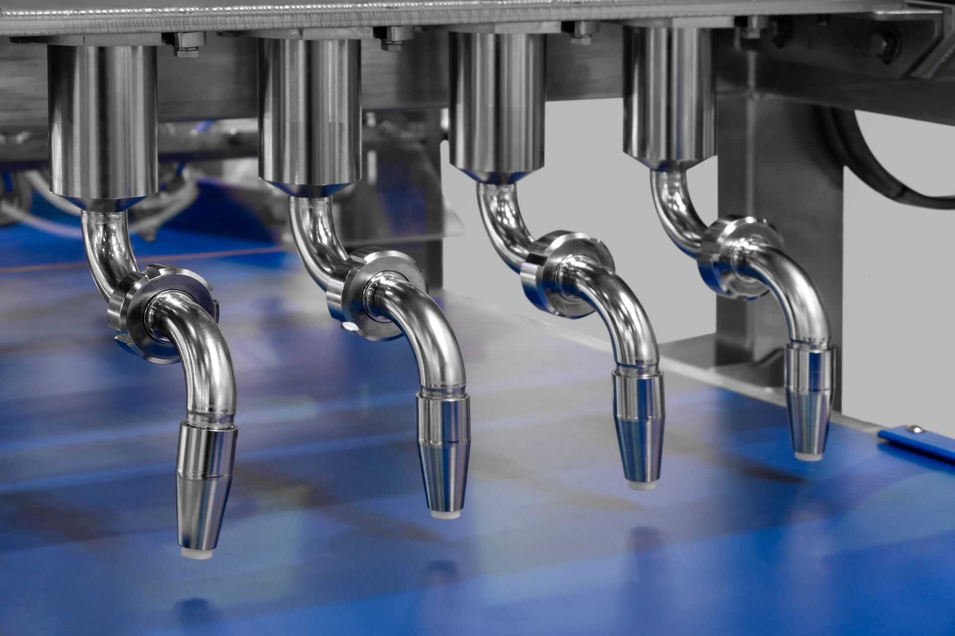 Un gros plan d'une machine avec des tuyaux en acier inoxydable sur une surface bleue.