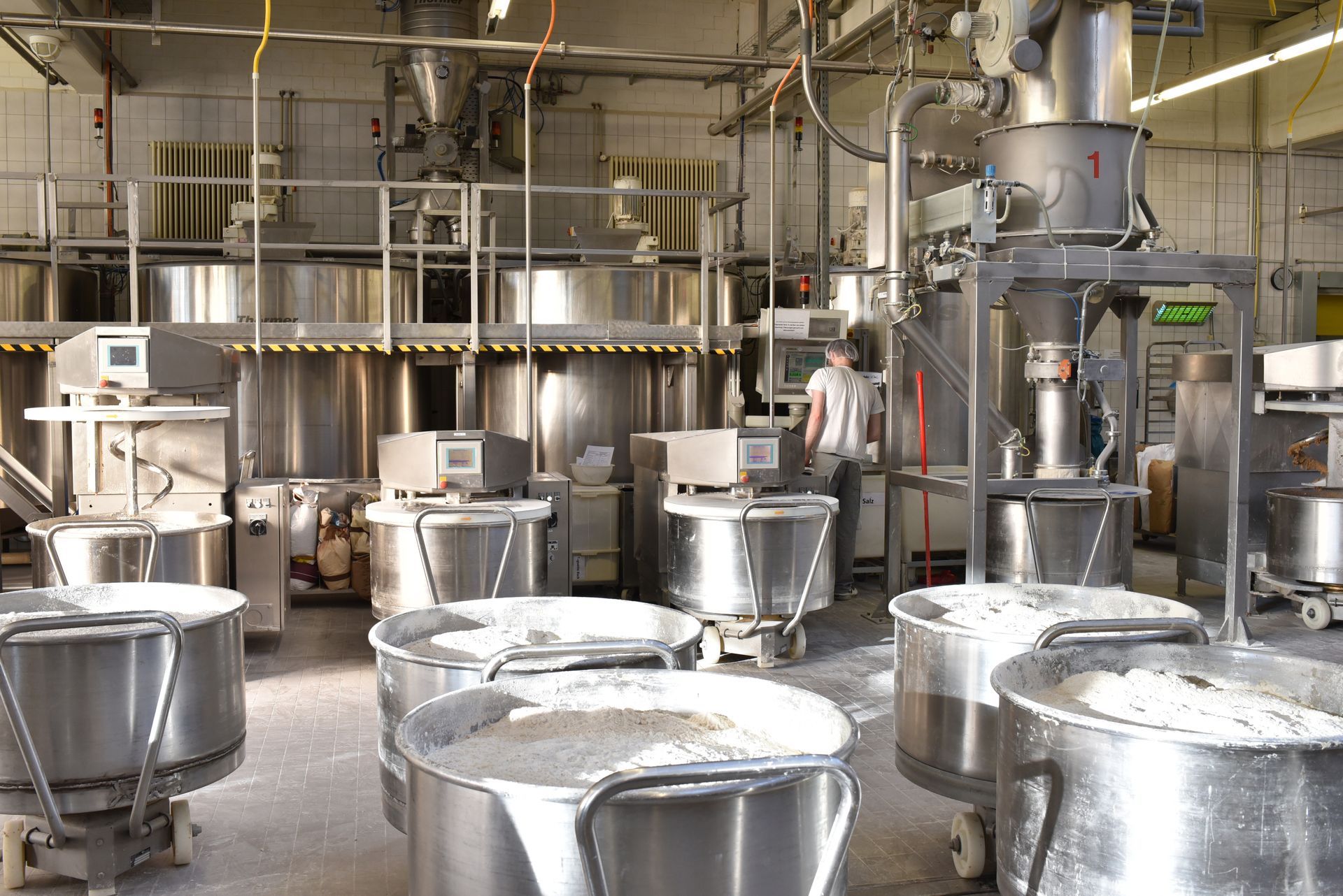 Une boulangerie remplie de nombreux bols et mélangeurs en acier inoxydable.