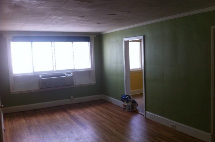 An empty living room with green walls and hardwood floors