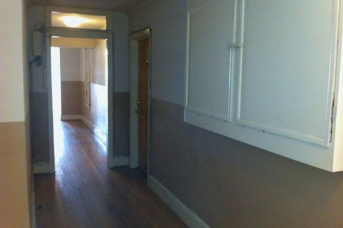 A hallway with wooden floors and white cabinets