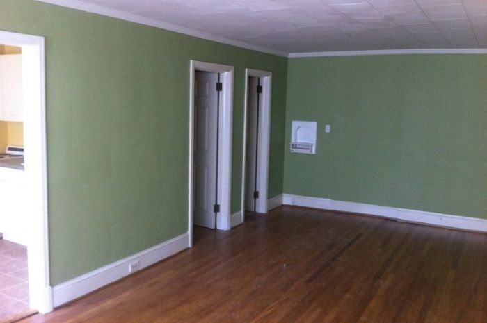 An empty room with green walls and hardwood floors