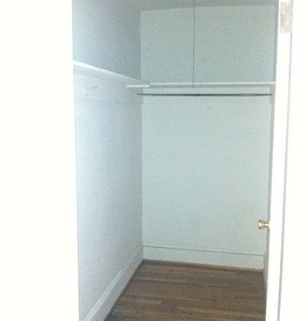 An empty closet with a wooden floor and white walls