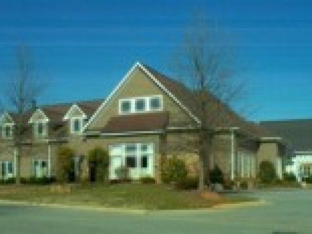 A large house with a triangle shaped roof is sitting on the side of the road.