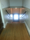 A staircase with a wooden floor and handrails leading up to a doorway.