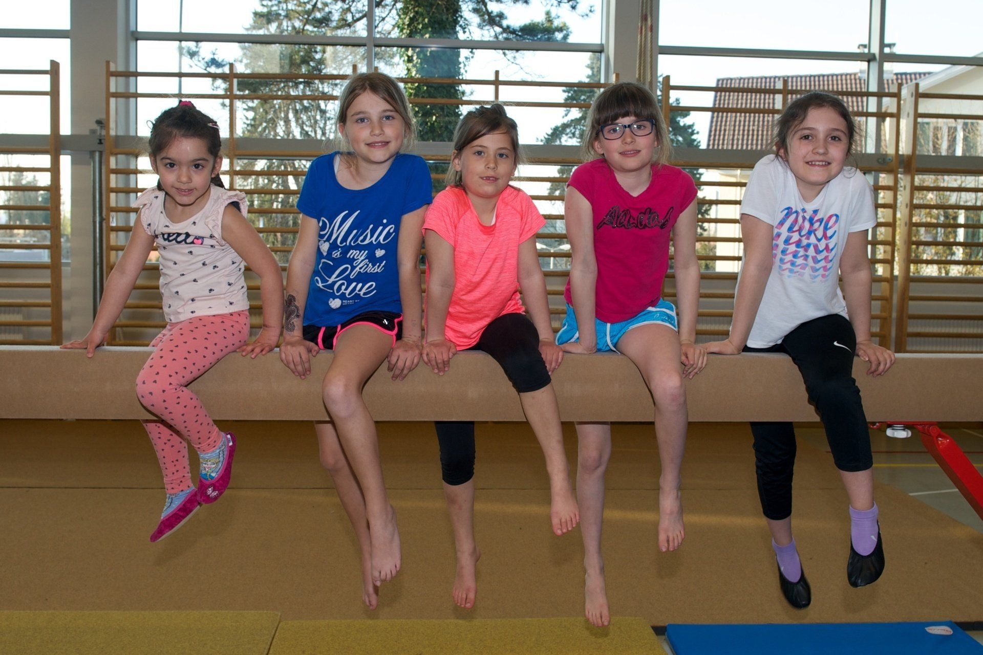 Eine Gruppe junger Mädchen sitzt auf einem Schwebebalken