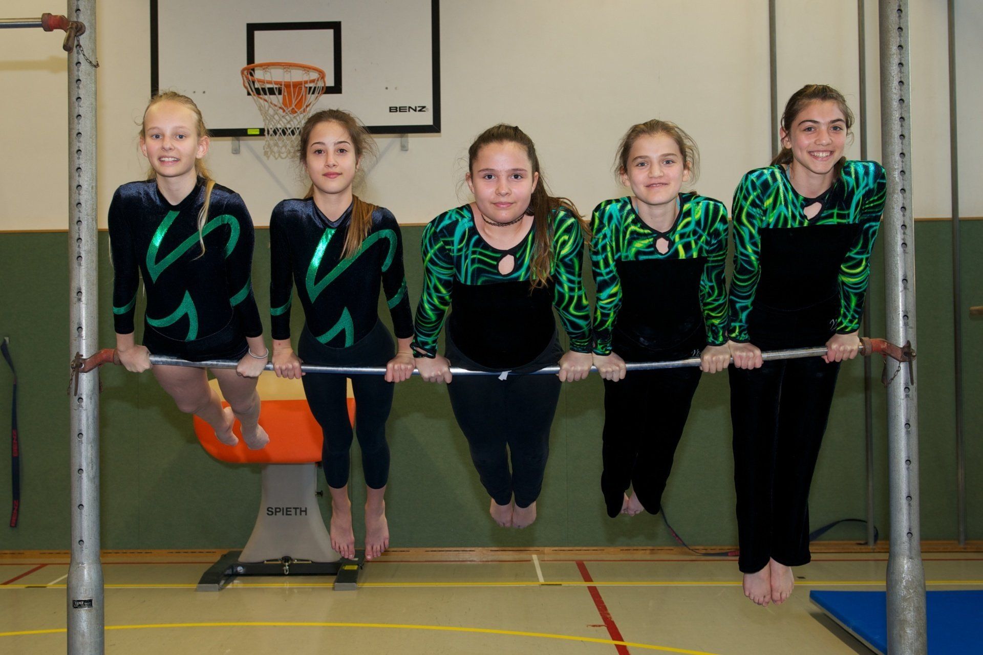Eine Gruppe junger Mädchen steht an Barren in einer Turnhalle
