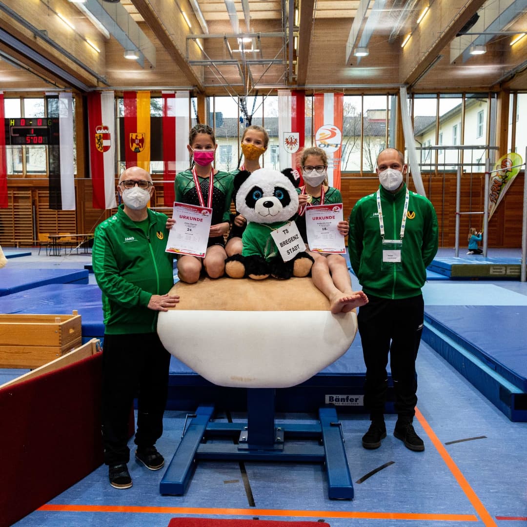 Eine Gruppe von Menschen mit Gesichtsmasken posiert mit einem ausgestopften Pandabären