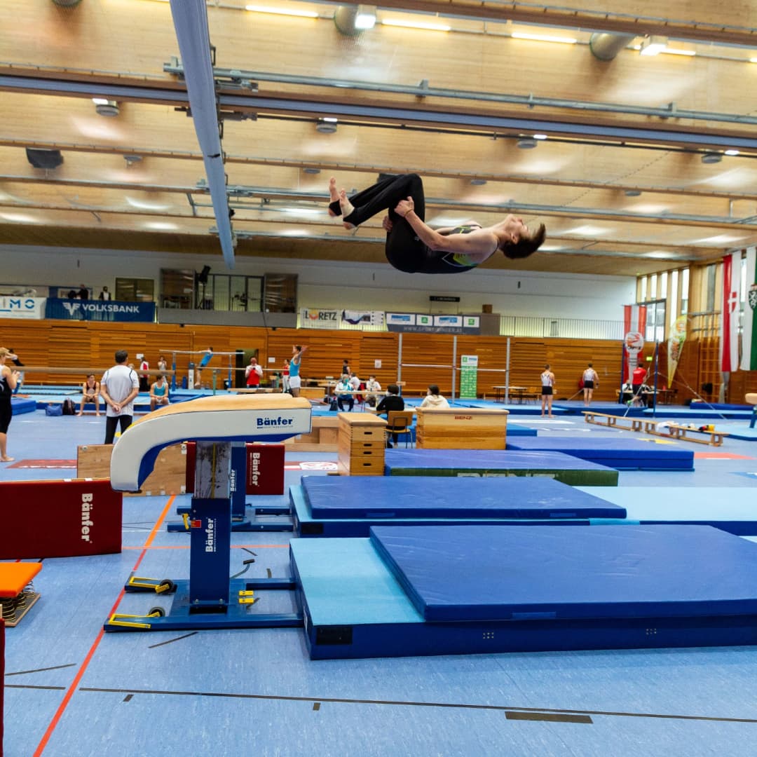 Ein Mann macht einen Handstand in einem Fitnessstudio mit einem Schild mit der Aufschrift „Bauer“ darauf