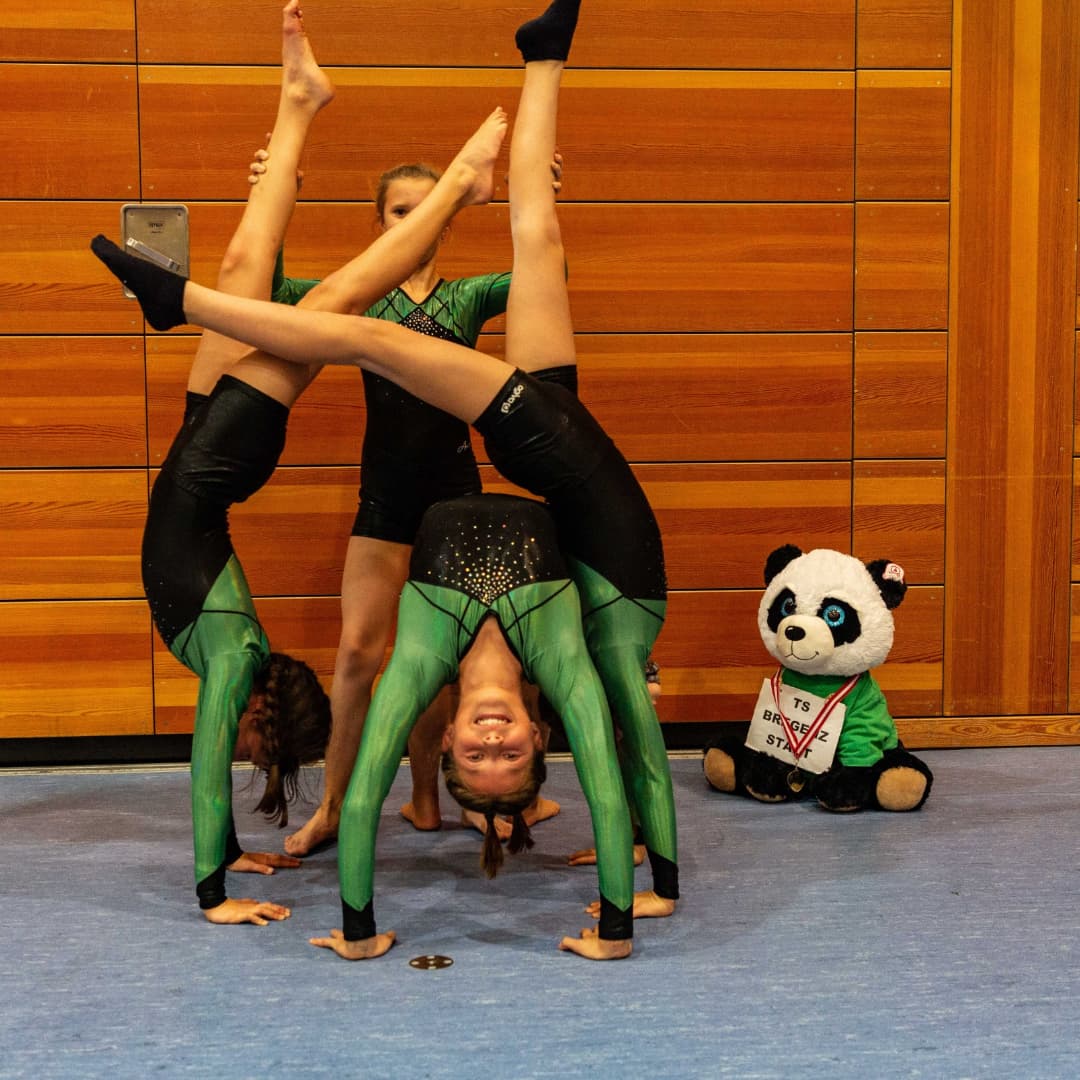 Ein Pandabär sitzt neben einer Gruppe von Turnern