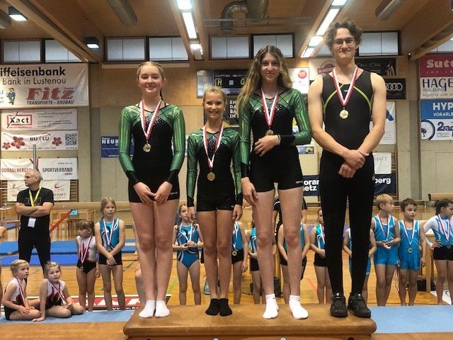 Eine Gruppe von Turnern steht auf einem Podium mit Medaillen um den Hals