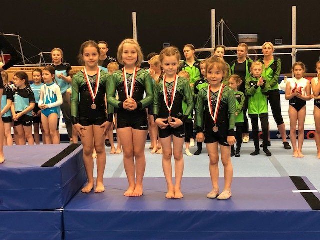 Eine Gruppe junger Mädchen steht mit Medaillen um den Hals auf einem Podium