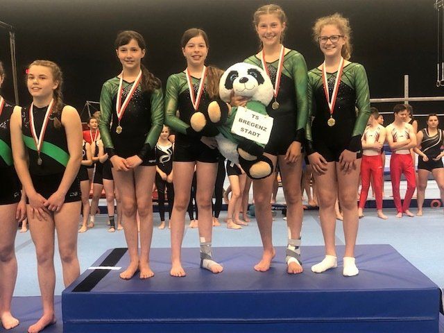 Eine Gruppe junger Mädchen steht mit einem Panda-Maskottchen auf einem Podium