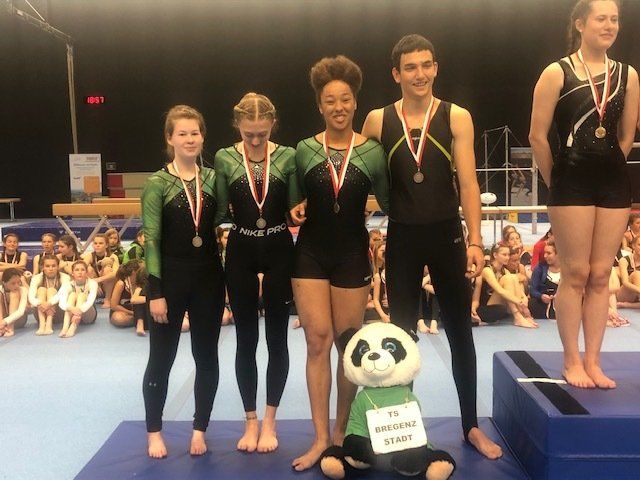 Eine Gruppe von Turnern posiert für ein Foto mit einem Panda-Maskottchen