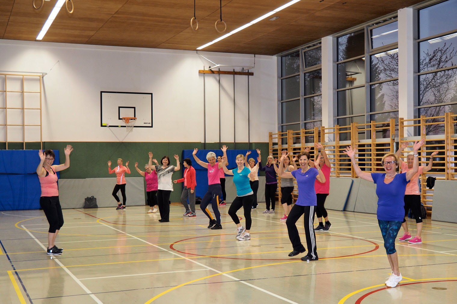 Eine Gruppe Frauen tanzt in einer Turnhalle.