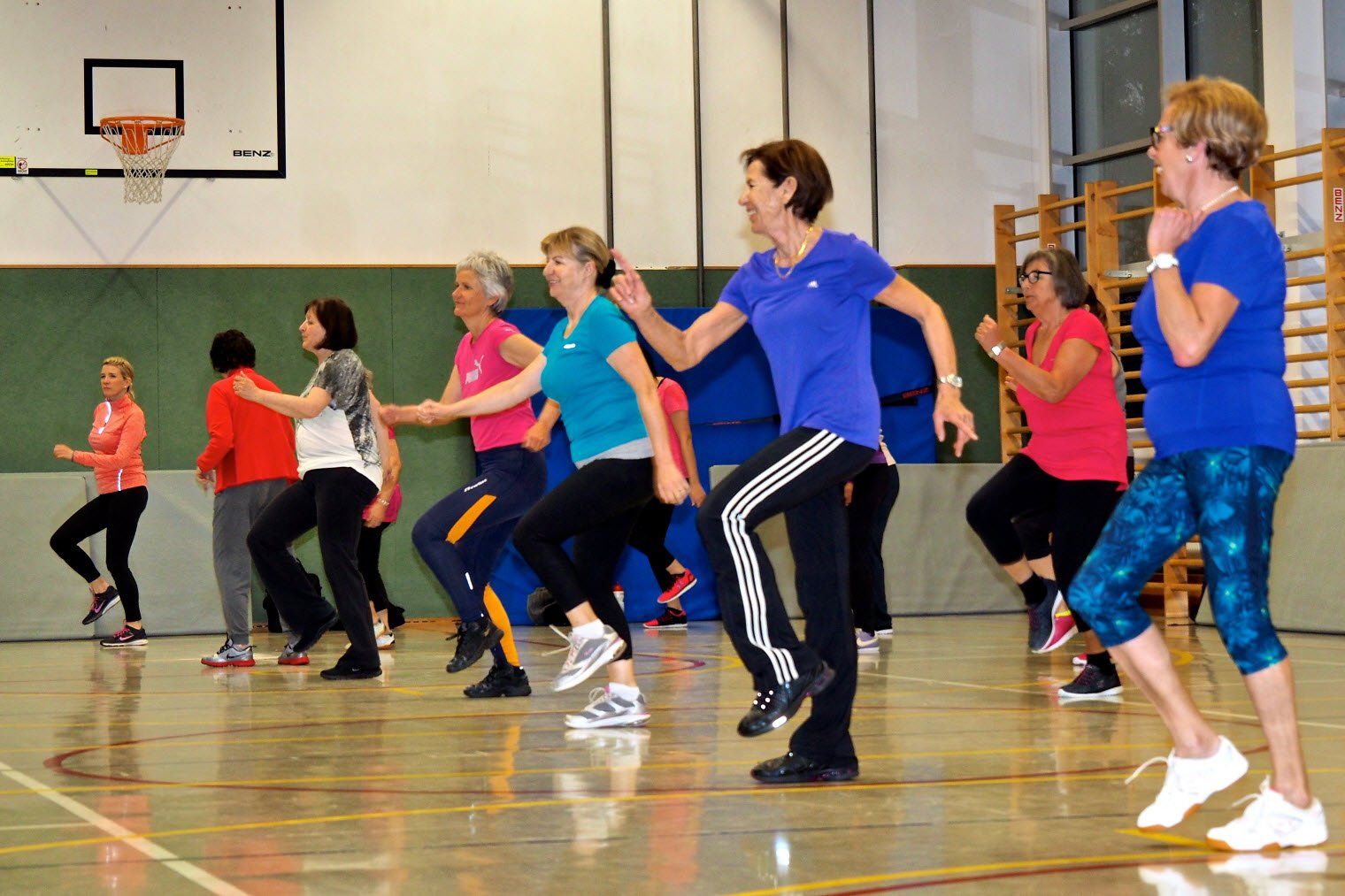 Eine Gruppe Frauen tanzt in einer Turnhalle.