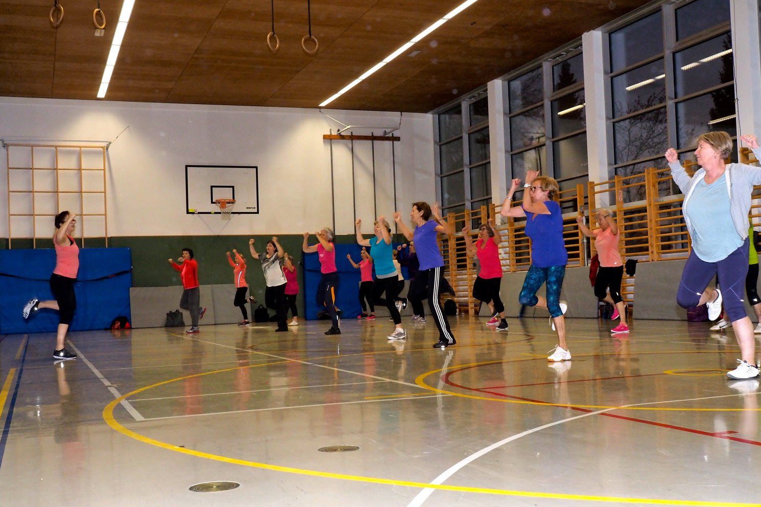 Eine Gruppe von Leuten tanzt in einer Turnhalle.