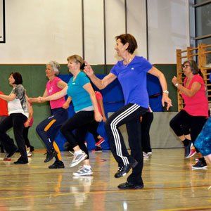 Eine Gruppe von Frauen tanzt auf dem Boden einer Turnhalle