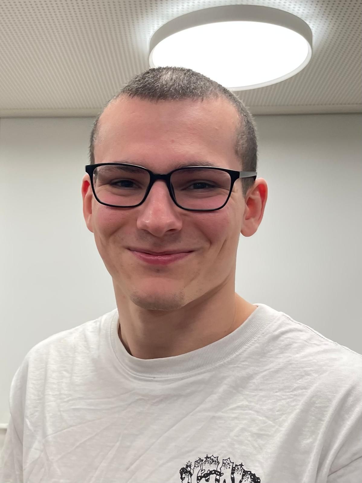 Ein Mann in einem schwarzen Hemd lächelt in die Kamera.