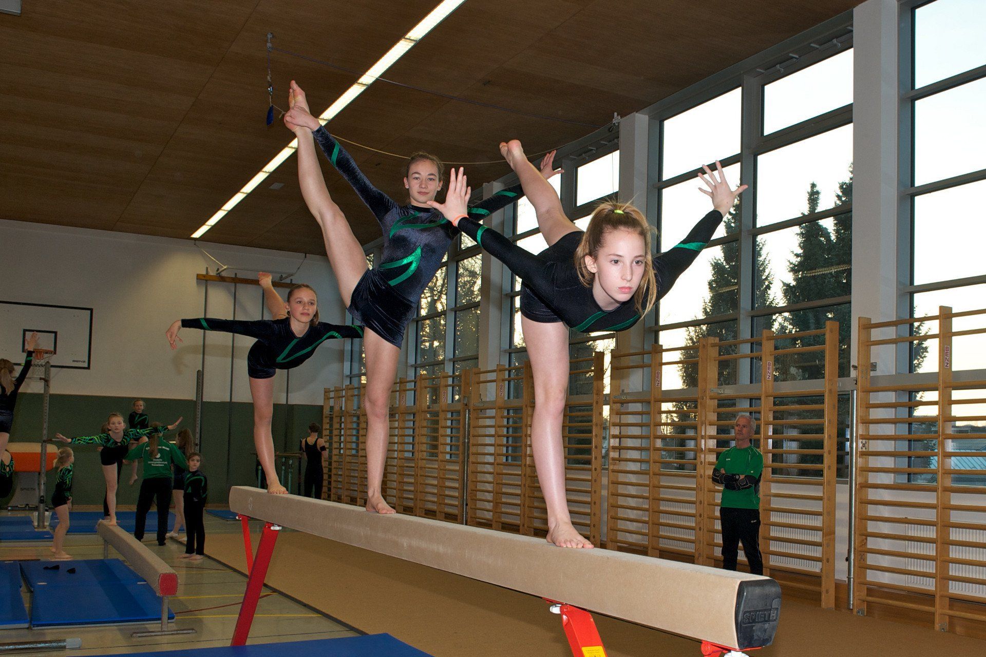 Eine Gruppe junger Mädchen macht Übungen auf einem Schwebebalken