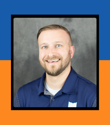 Smiling man in a navy polo shirt against a gray background.