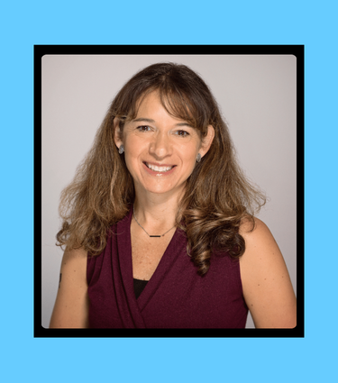 Woman smiling, wearing a sleeveless maroon top and a thin necklace.