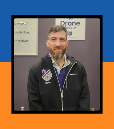 Man in a black jacket stands in front of a Drone Soccer sign.