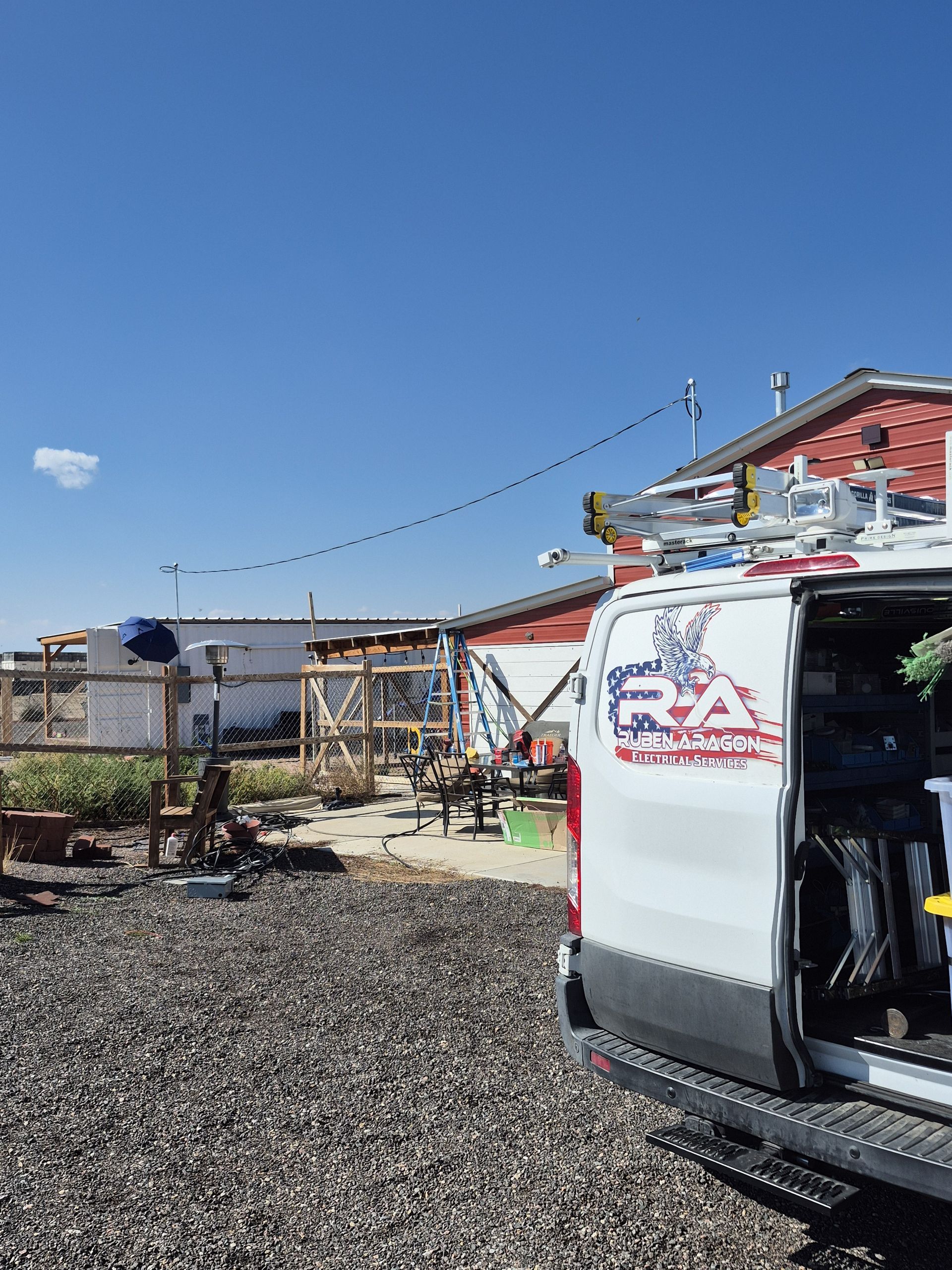 White van with open back, electrical work scene, blue sky.