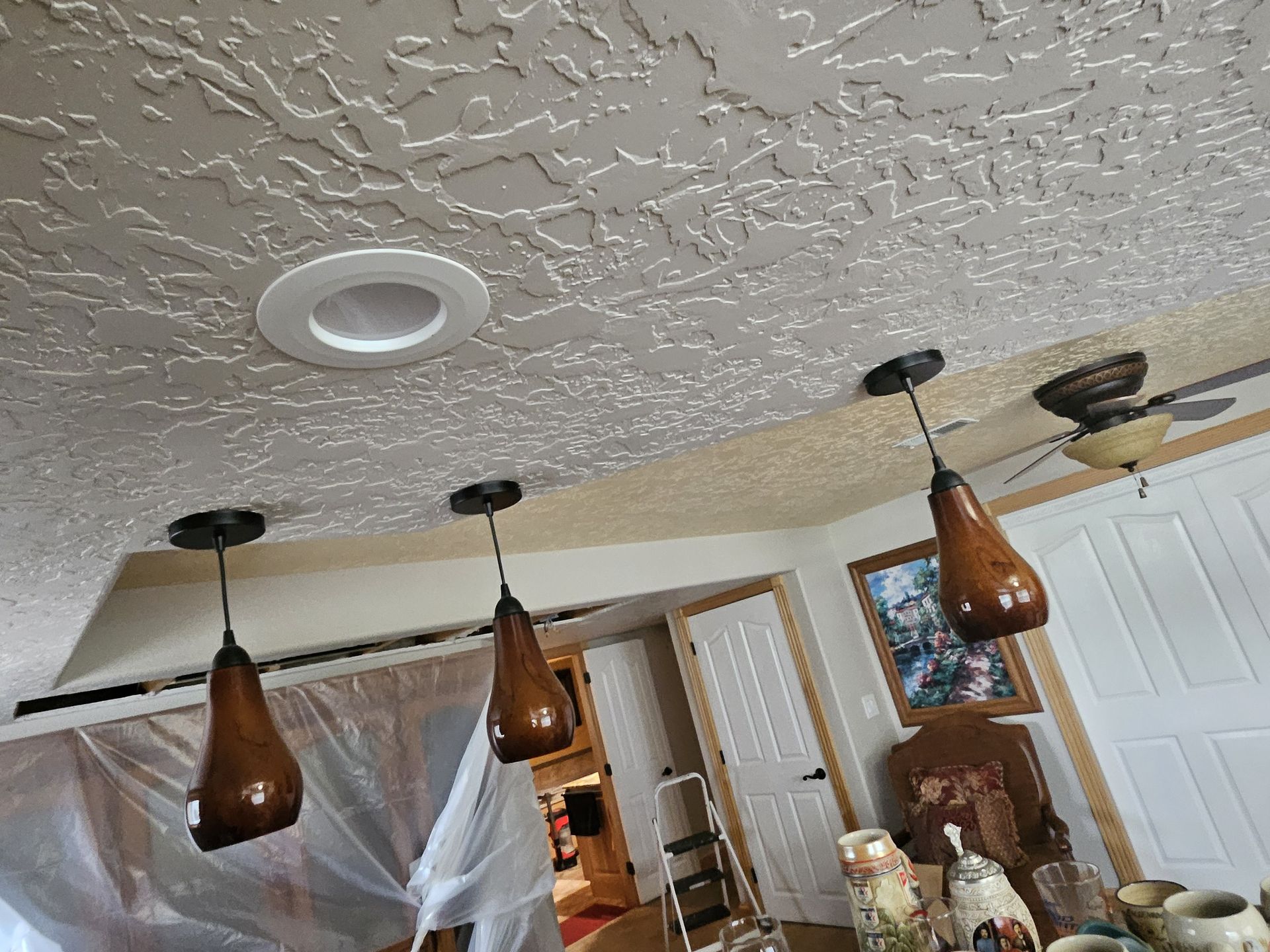 Three teardrop-shaped pendant lights hang from a textured ceiling. A recessed light and a ceiling fan are also visible.