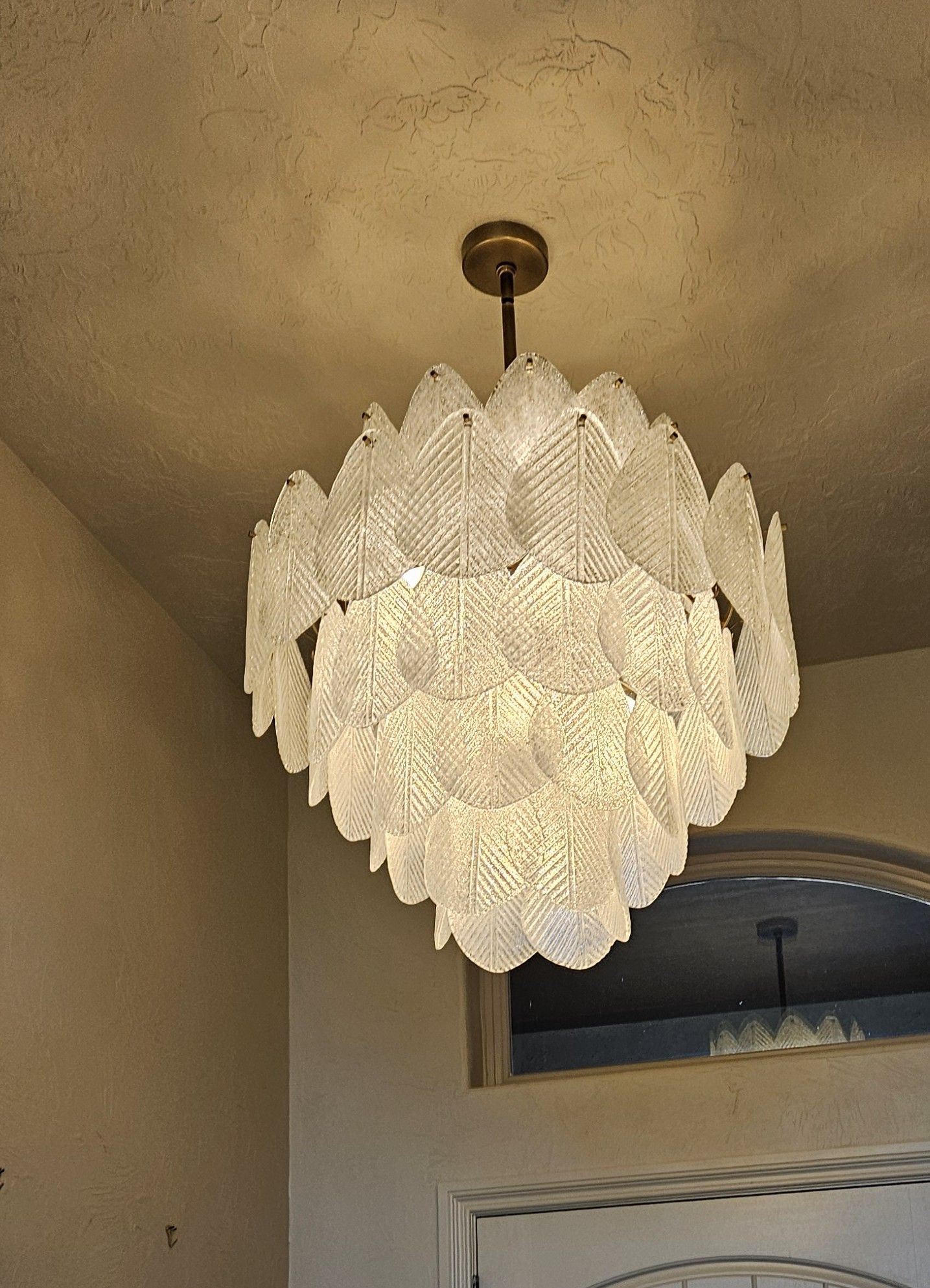 Chandelier with layers of glass leaves hanging from ceiling.