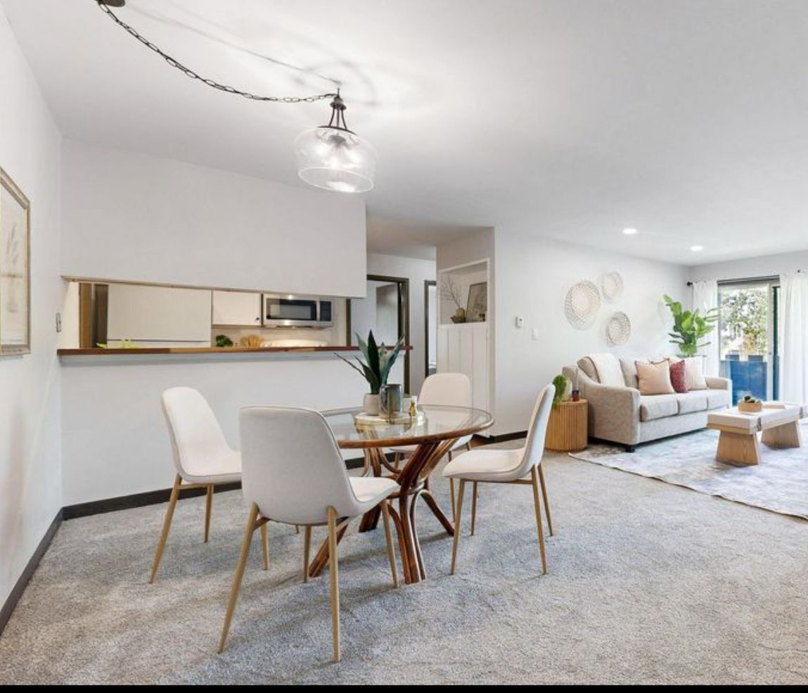 Open-concept living space with dining area, kitchen, and living room; light-colored decor.