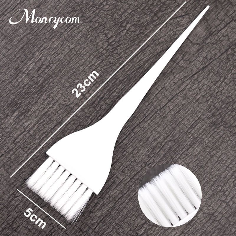 La mano de una persona sostiene un pincel aplicador de tinte para el cabello de plásticosobre un fondo oscuro texturizado.