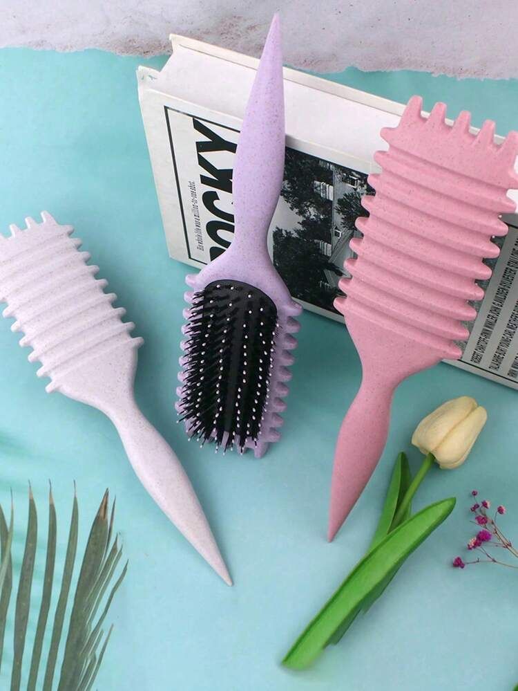 Tres cepillos rectangulares para el cabello con puntas en forma de orejas de gato, colocados sobre una suave tela blanca.