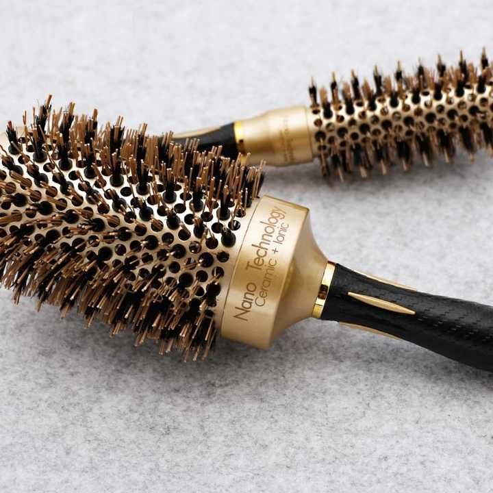 Un cepillo redondo de color dorado y negro con mango puntiagudo, etiquetado como 53#.