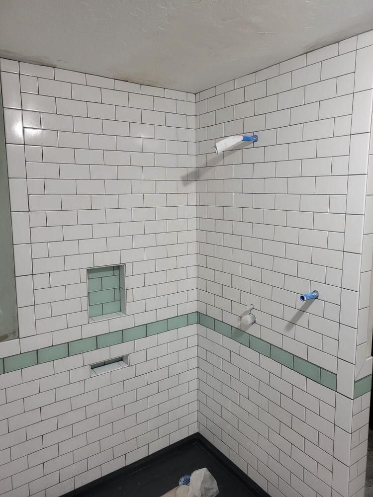 Empty tiled shower under construction with white subway tiles and exposed plumbing fixtures